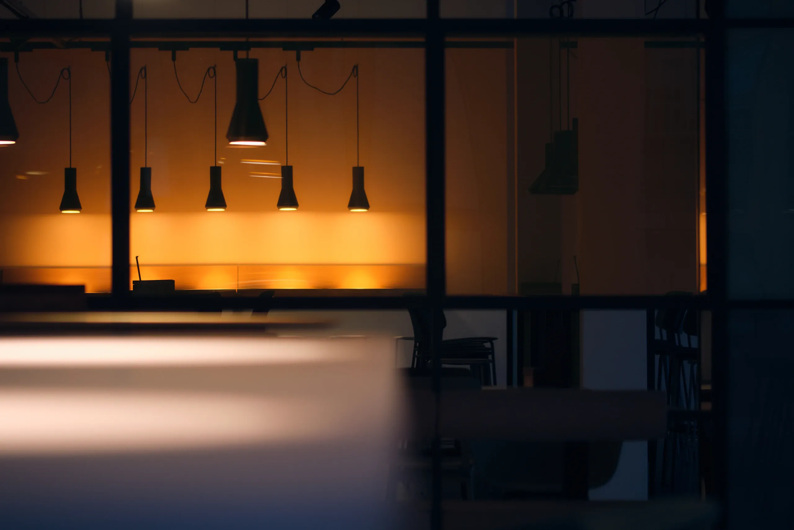 Warm beleuchtete Pendelleuchten in einem Büro, dezent verschwommen.