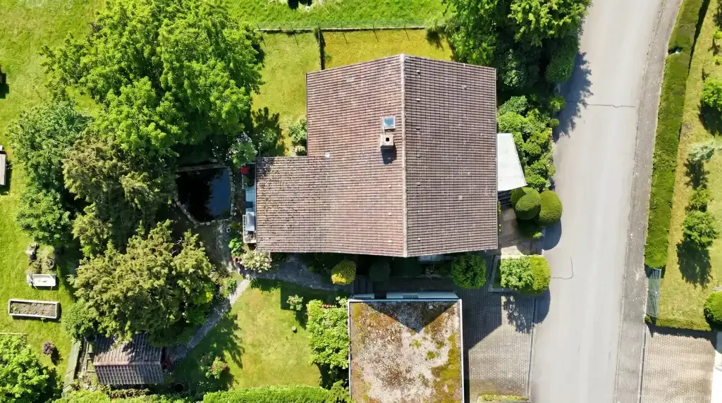 Luftaufnahme eines Einfamilienhauses mit Ziegeldach und großem Garten an einer Straße in Heilbronn.